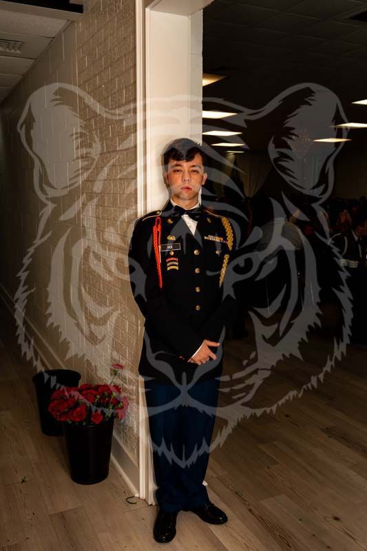 A person in a formal military dress uniform stands in a doorway, superimposed with a faded, semi-transparent tiger graphic.