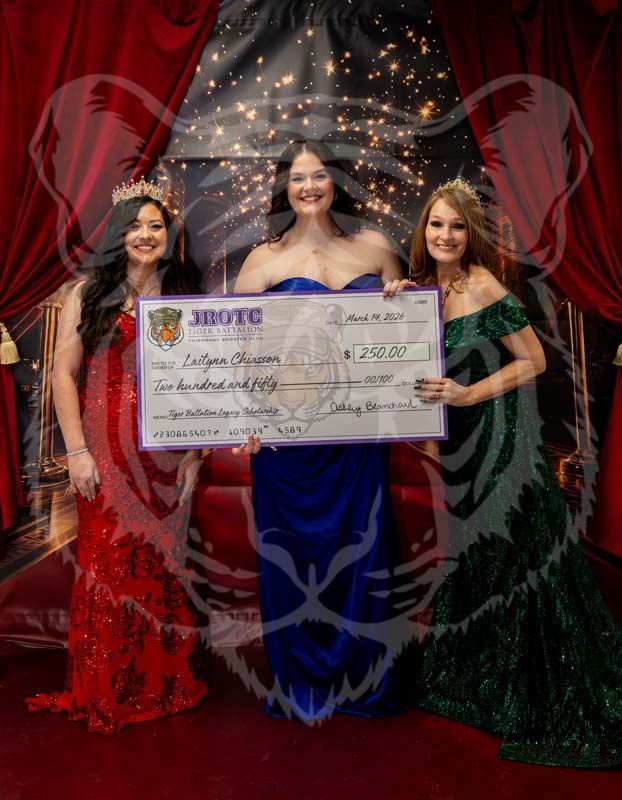 Three people in gowns stand on a red carpet holding a large ceremonial check at an event with red curtains and lights.