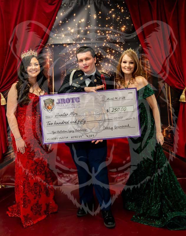 Three people in formal wear stand on stage holding a large JROTC ceremonial check against a red curtain background.