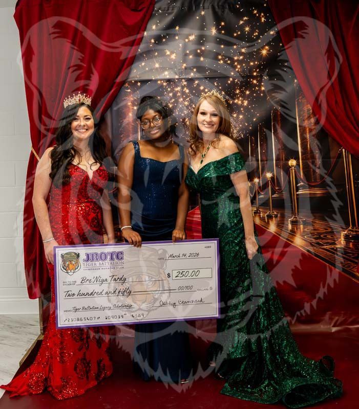 Three people in formal gowns hold a large check against a backdrop with red curtains and a gold-light design.