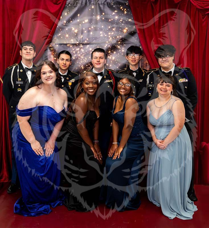 A group of ten people in formal attire posing for a photo against a backdrop of red curtains and string lights.