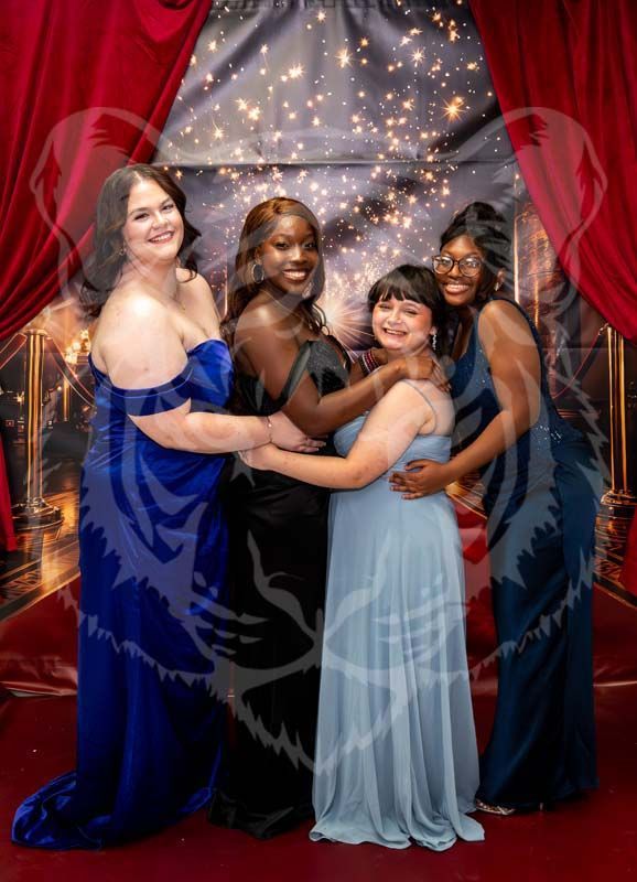 Four people in formal gowns pose together in front of a backdrop with red curtains and sparkling lights.