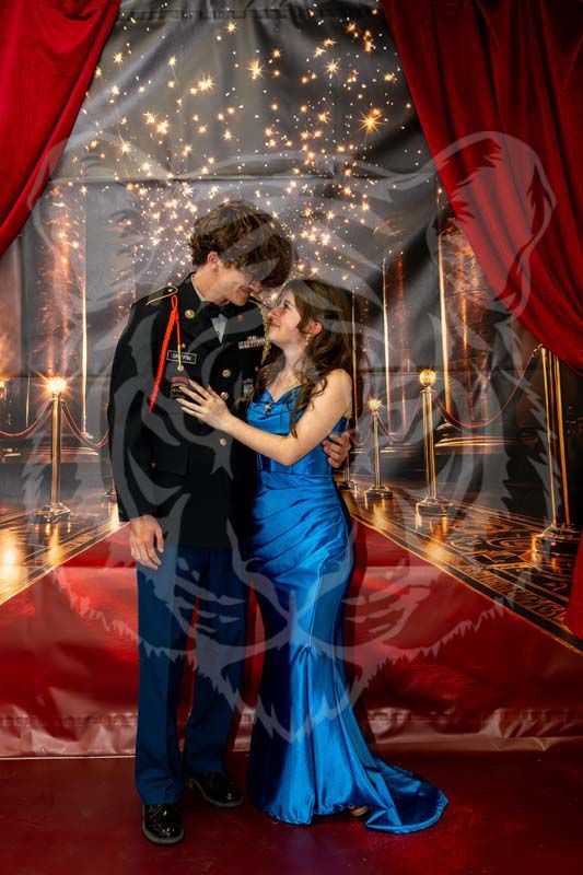 A person in a dark formal military uniform and a person in a bright blue satin gown stand together in a romantic pose.