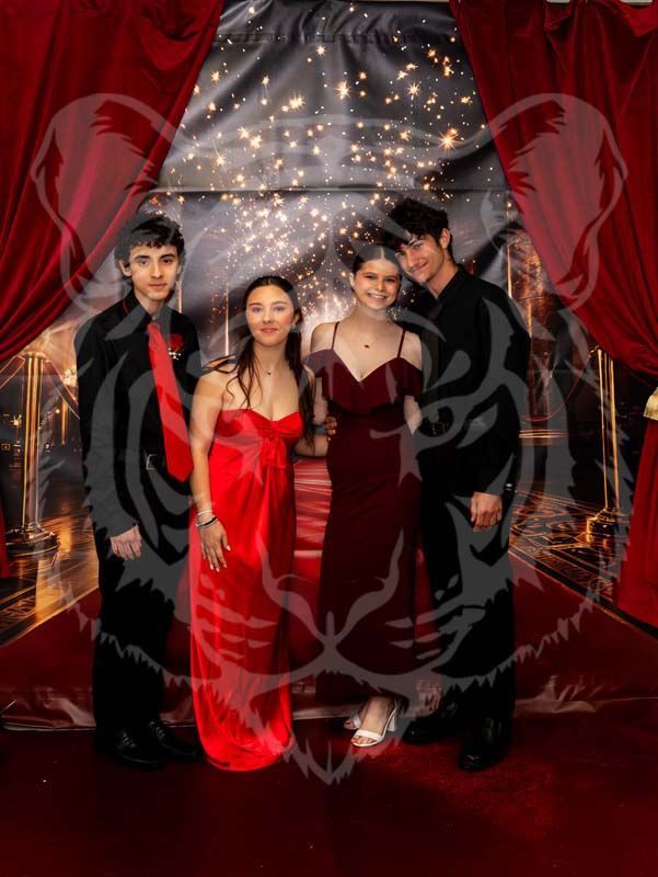Four people pose for a photo in formal attire in front of a red-curtained backdrop with a faded tiger graphic overlay.
