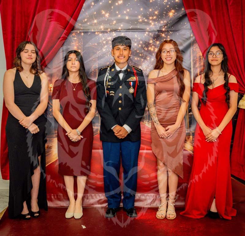 A group of five people stand in a line before a red curtain backdrop, posing for a formal photo.