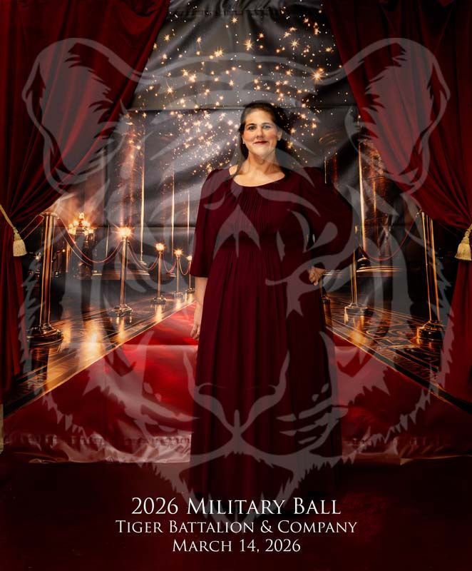 A person in a maroon dress stands on a red carpet at a 2026 Military Ball, overlaid with a faint tiger graphic.