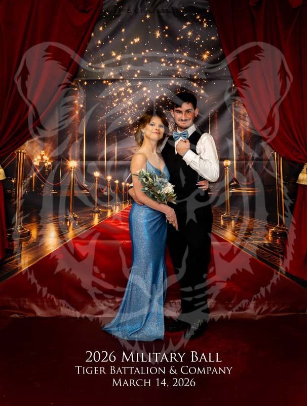 A couple in formal attire stands on a red carpet in front of a backdrop, with a semi-transparent tiger graphic overlaid.