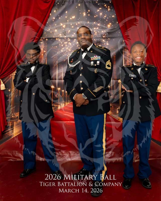 Three individuals in military dress uniforms pose on a red carpet in front of a backdrop for the 2026 Military Ball.