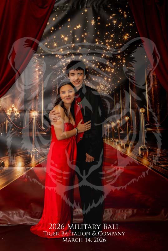 A formal portrait of two people posing together against a red-carpet event backdrop with a tiger watermark.