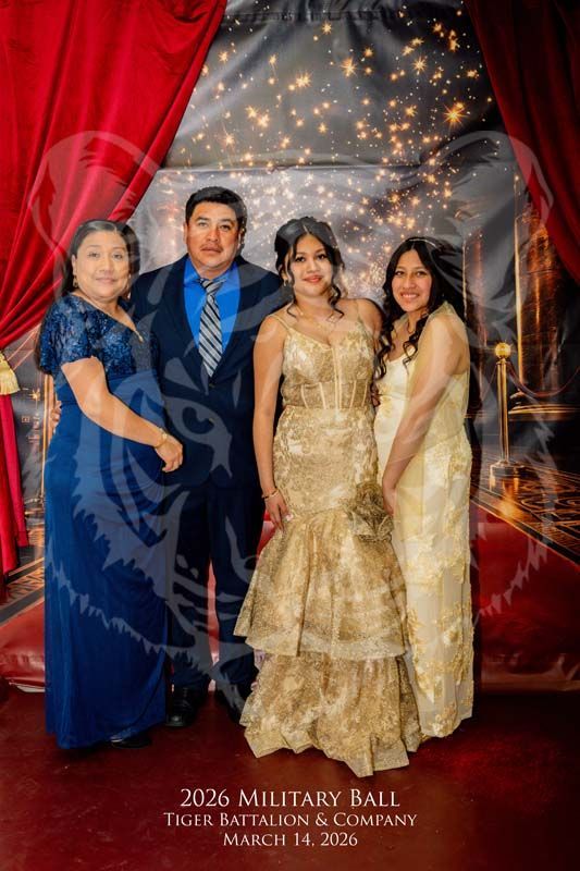 Four people pose for a formal photo in front of red curtains and string lights at a 2026 military ball.