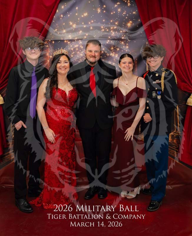Five people pose for a formal group portrait at a military ball against a backdrop with red curtains and lights.