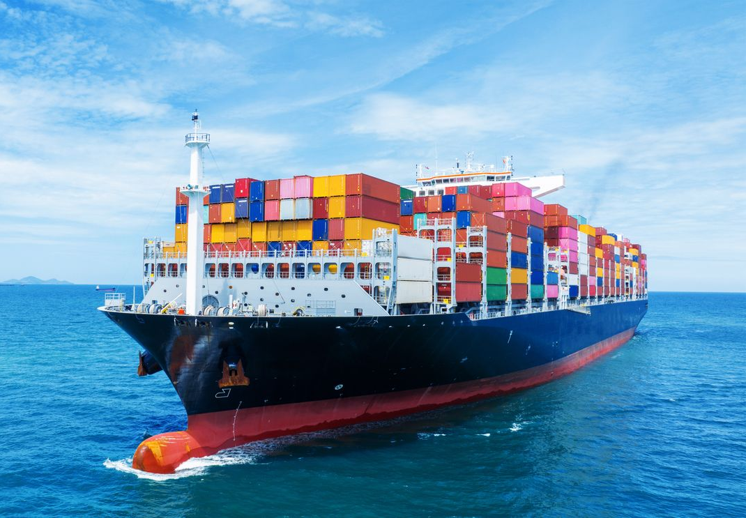 A group of cargo ships are docked in a harbor.