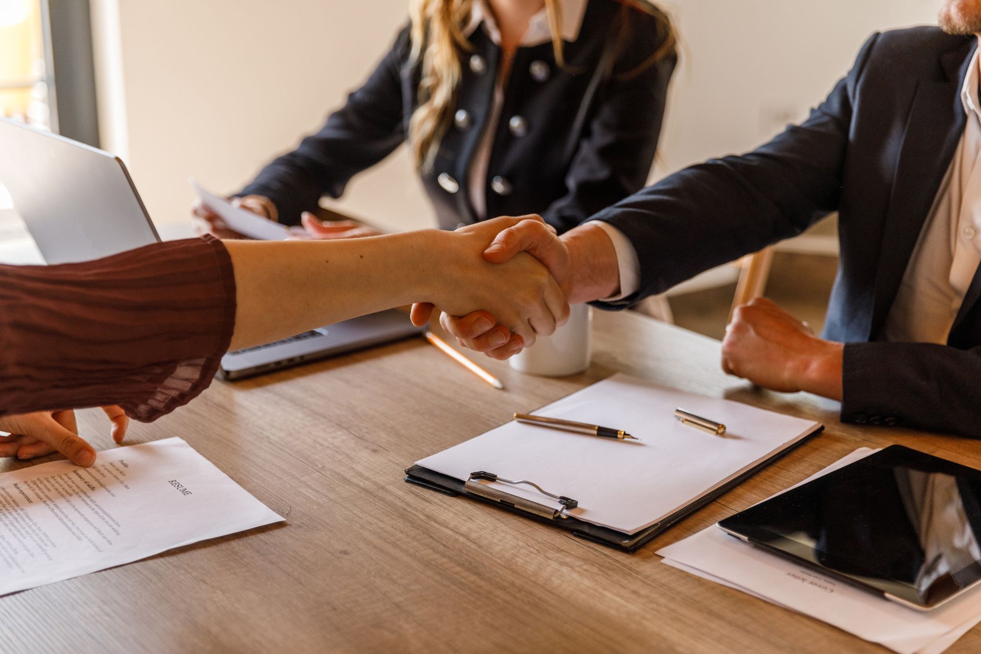 A man and a woman are shaking hands while sitting at a table.