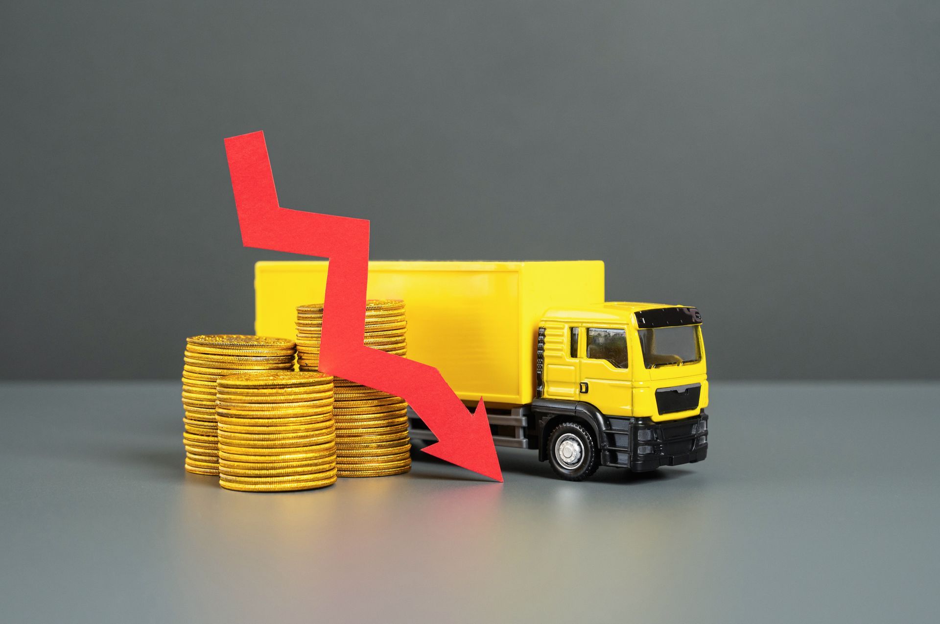 A toy truck is sitting next to a stack of gold coins with a red arrow pointing down.
