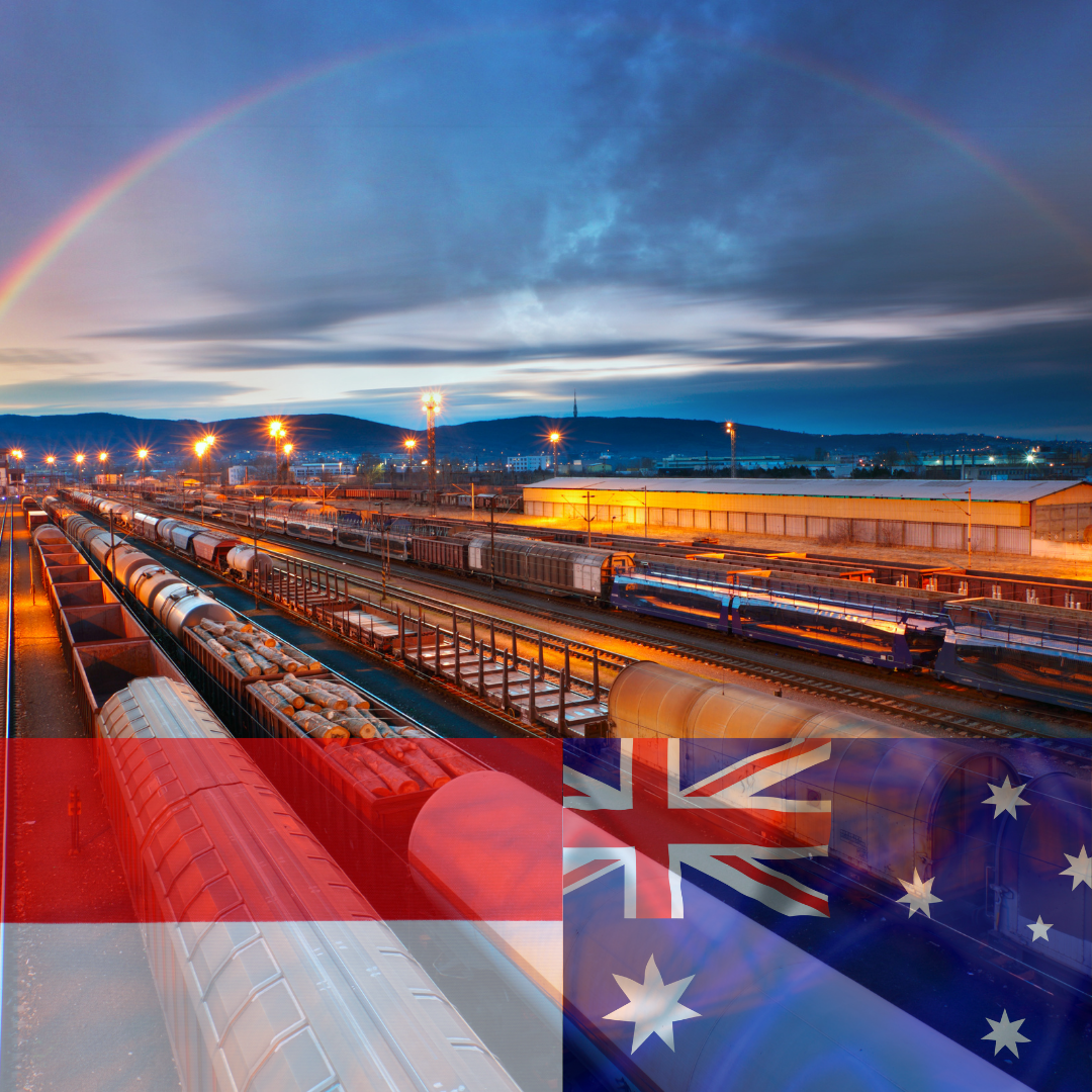 A train yard with a rainbow in the background and a flag in the foreground