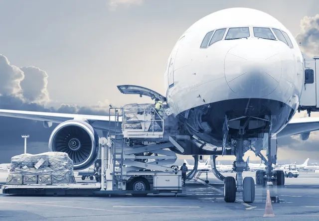 A large passenger jet is being loaded with cargo at an airport.