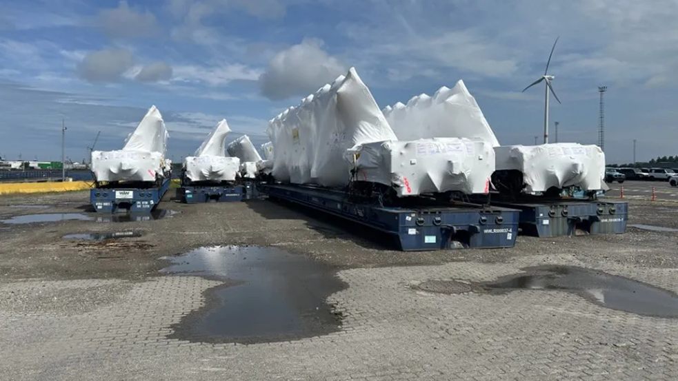 A large blue object is being lifted by a crane in a factory.