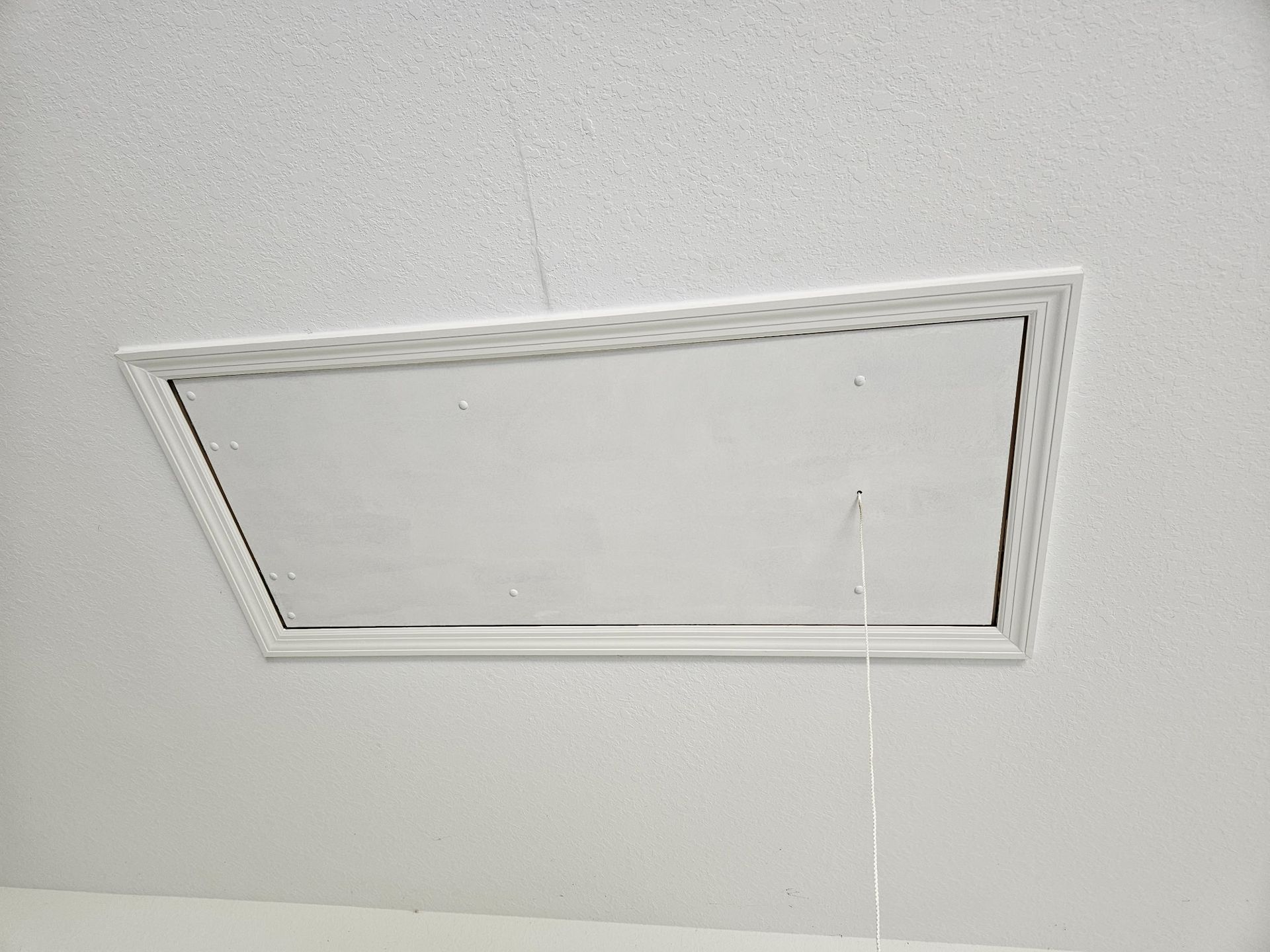 White ceiling with a rectangular access panel; a pull string hangs down.