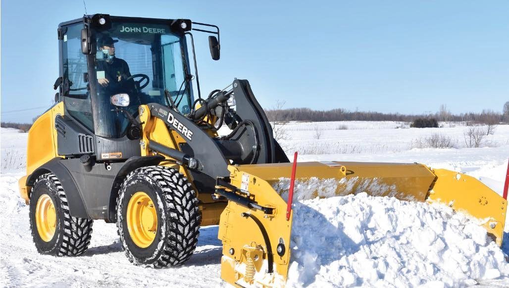 Une souffleuse à neige jaune déblaye la neige par une belle journée d'hiver. Une personne est assise dans la cabine.