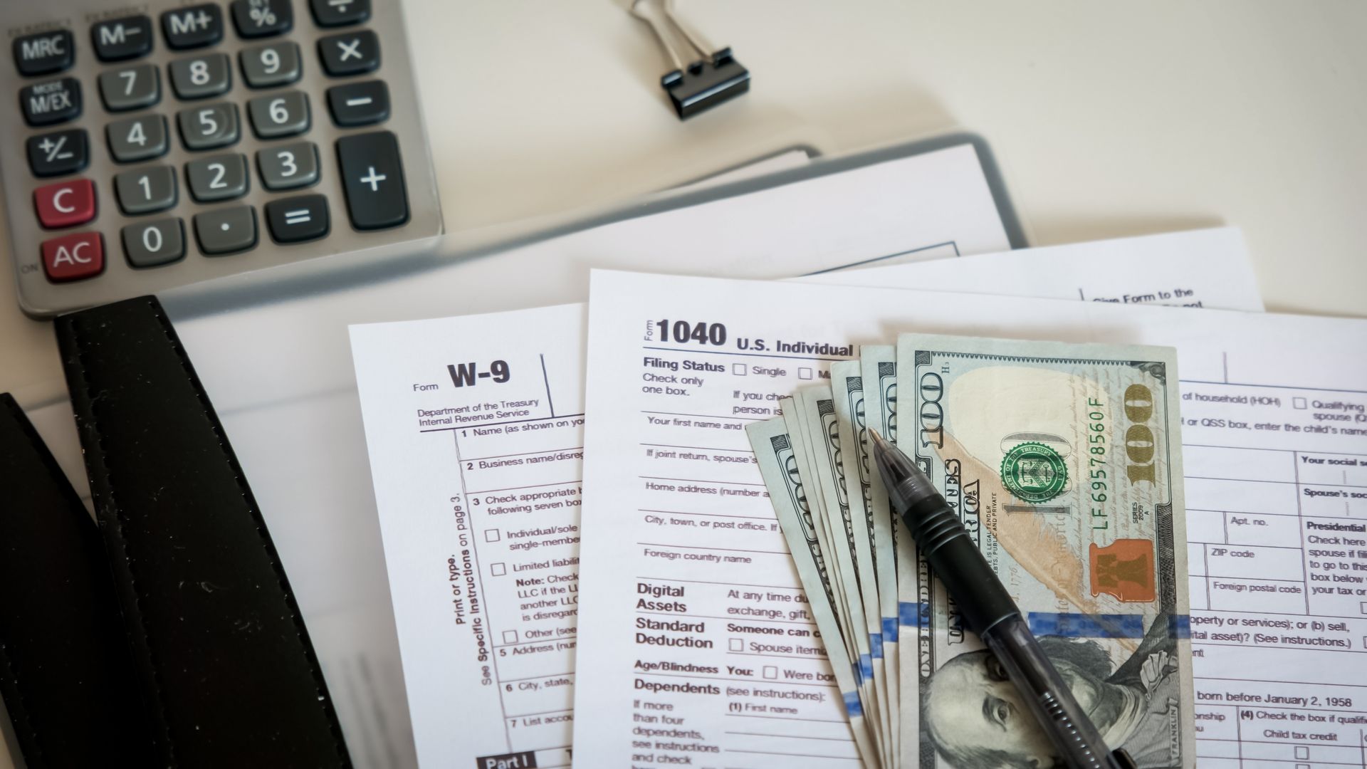 Calculator, tax forms, cash, and pen on a desk, suggesting IRS audit representation in NY.