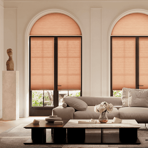 Minimalist living room with arched windows, tan blinds, beige sofa, and black coffee table