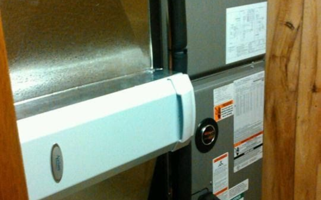 Metallic rectangular HVAC ductwork bends around the corner of a building.