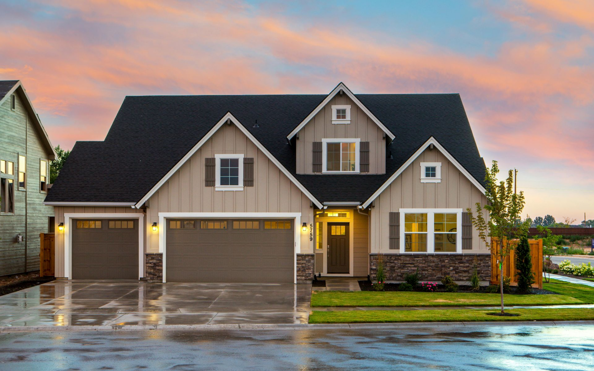 House exterior with tan siding, brown garage doors, and a colorful sunset sky.