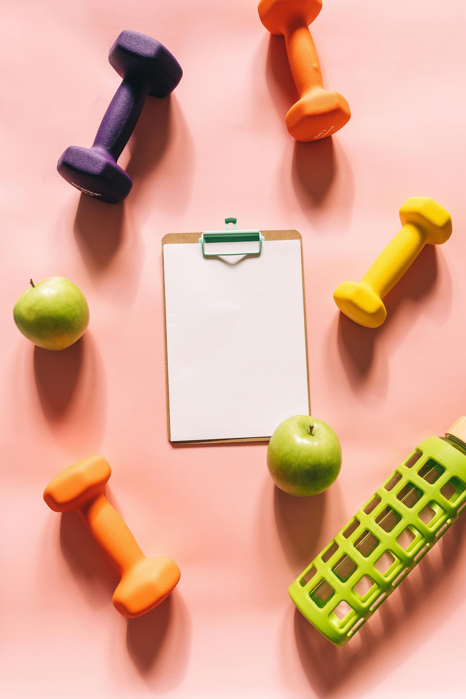 Dumbells and apples on a peach table