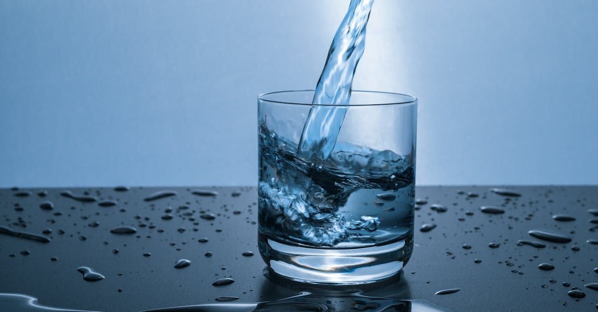 Water is being poured into a glass on a table.