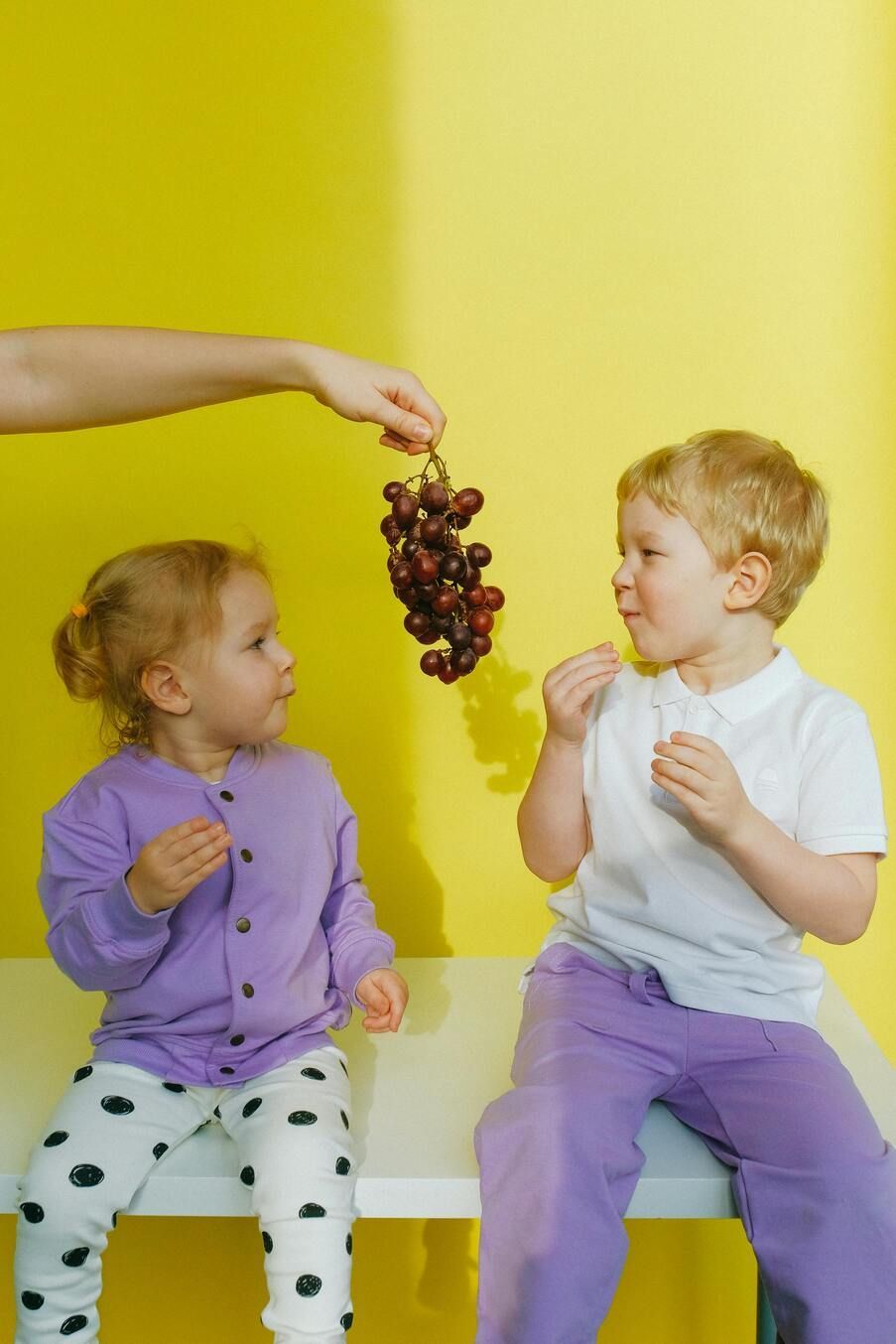 Two healthy kids eating grapes