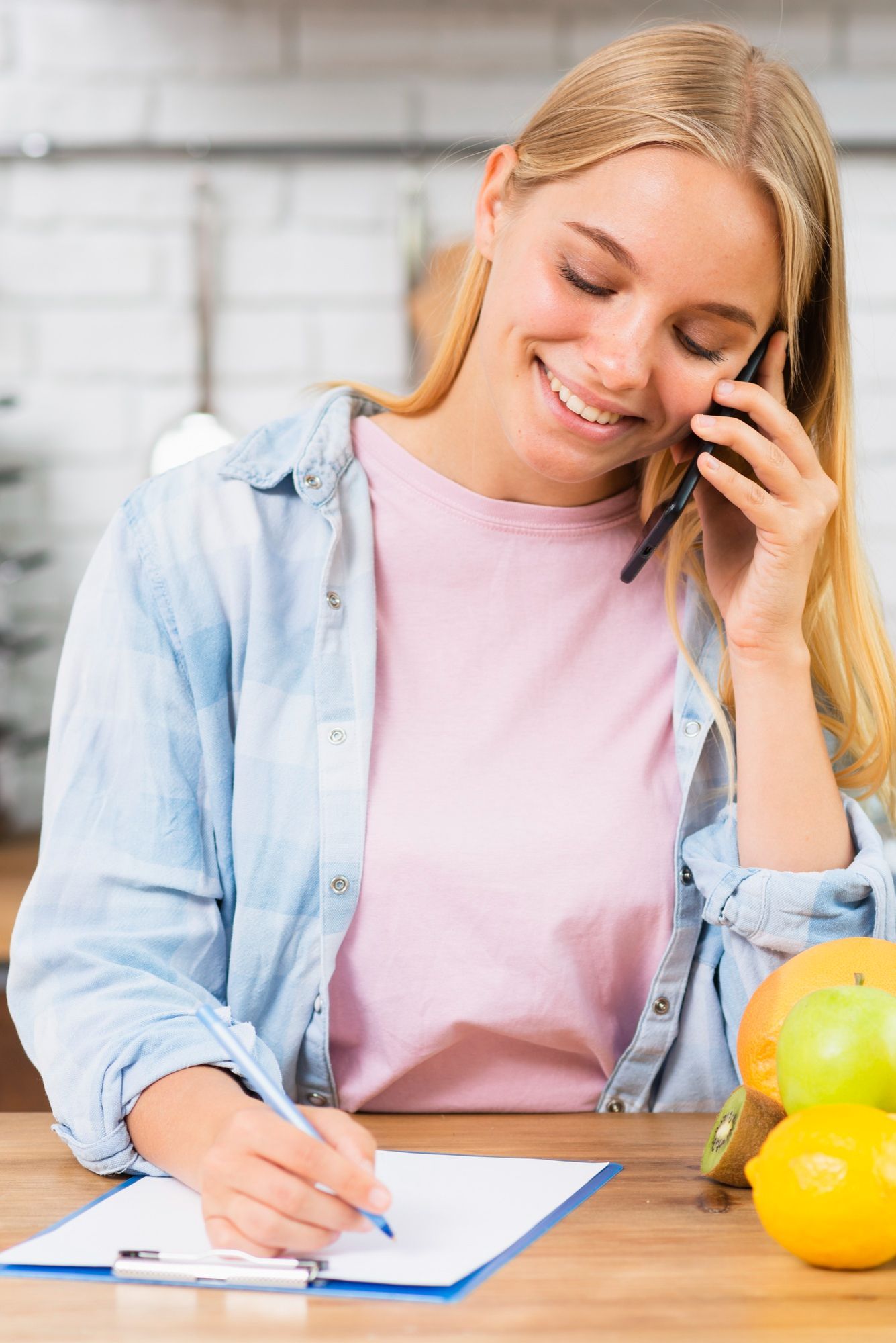woman talking on the phone, writing her meal plan.