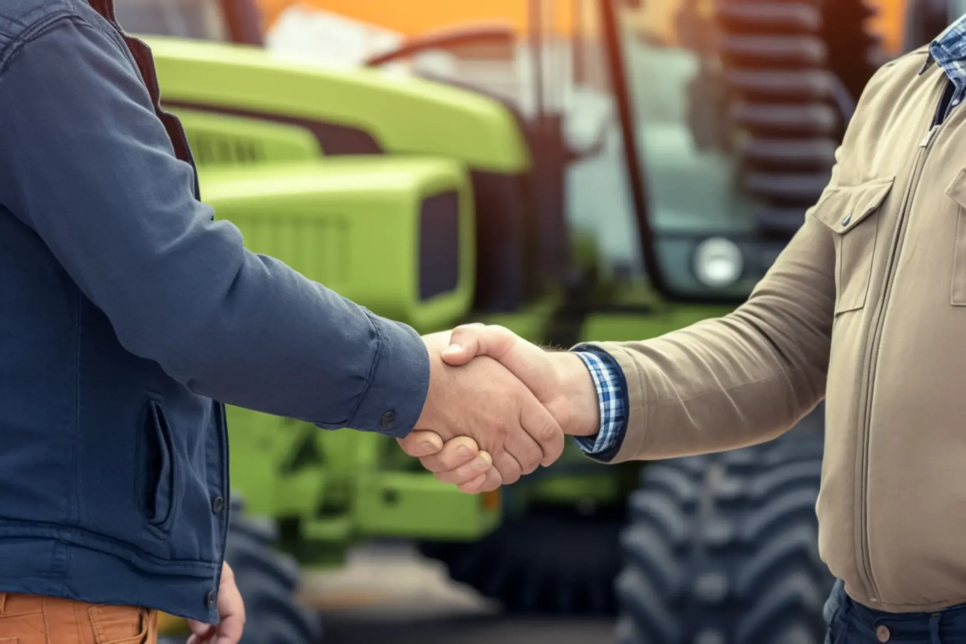 Two men are shaking hands in front of a tractor.