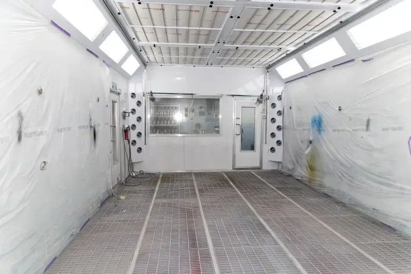 An Empty Paint Booth With White Walls And A Brick Floor — Spray Tech Smash Repairs In Gympie, QLD