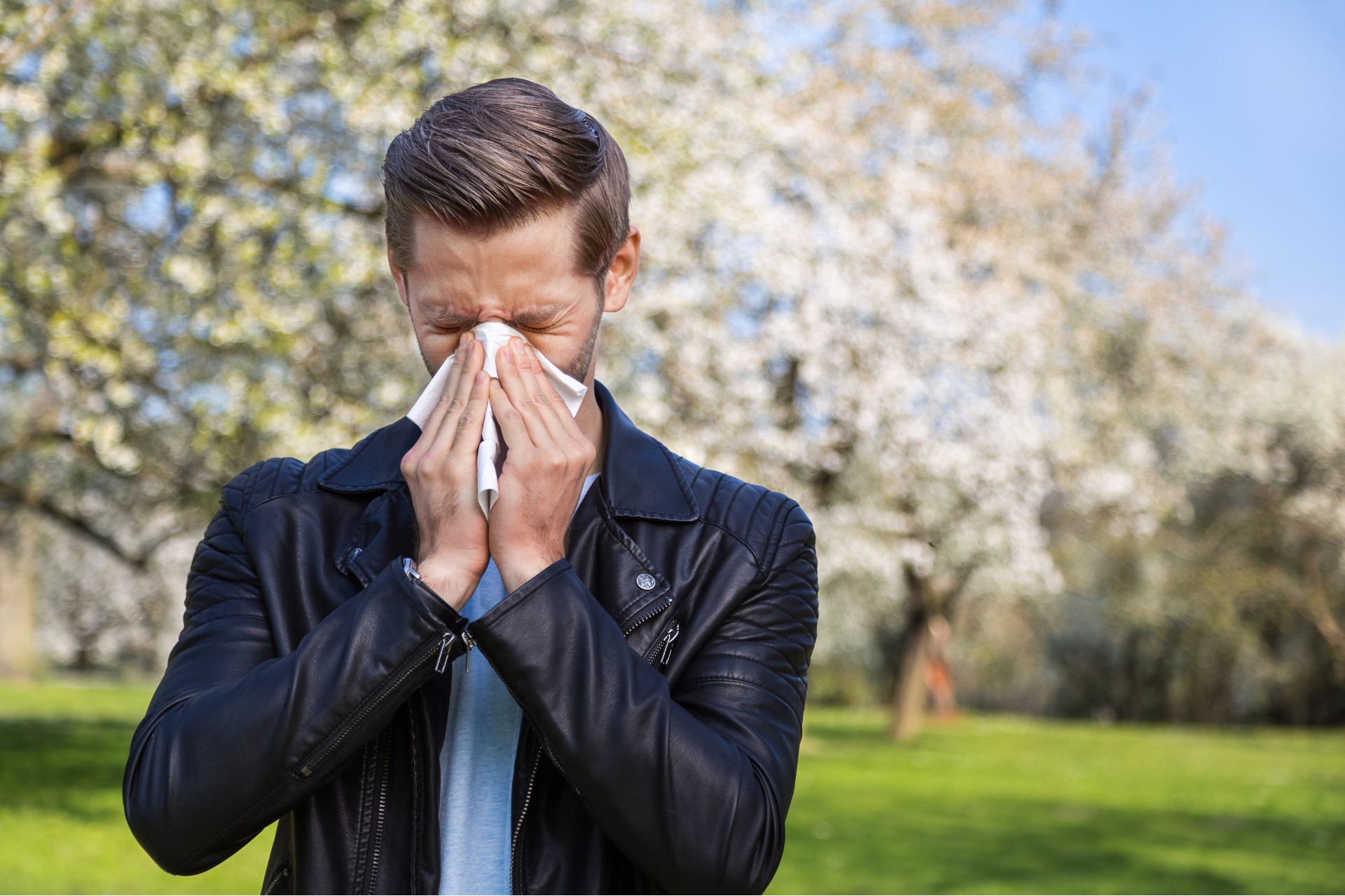 A man with allergies blows his nose