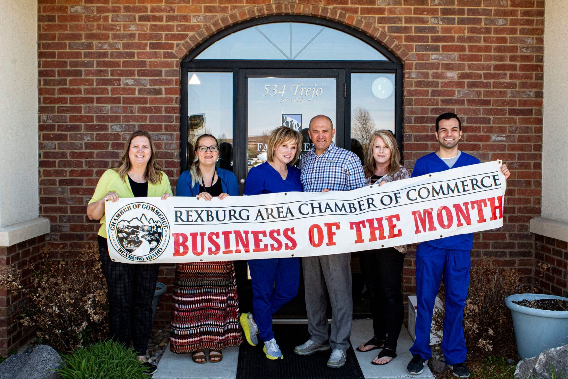 A group of people holding a sign that says business of the month