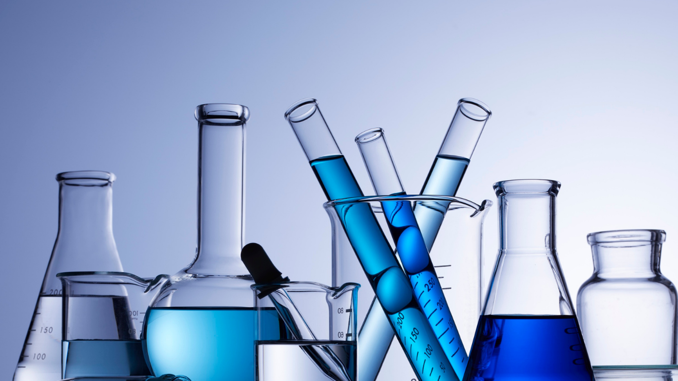 Laboratory glassware, including beakers, flasks, and test tubes filled with blue liquid against a light blue background.