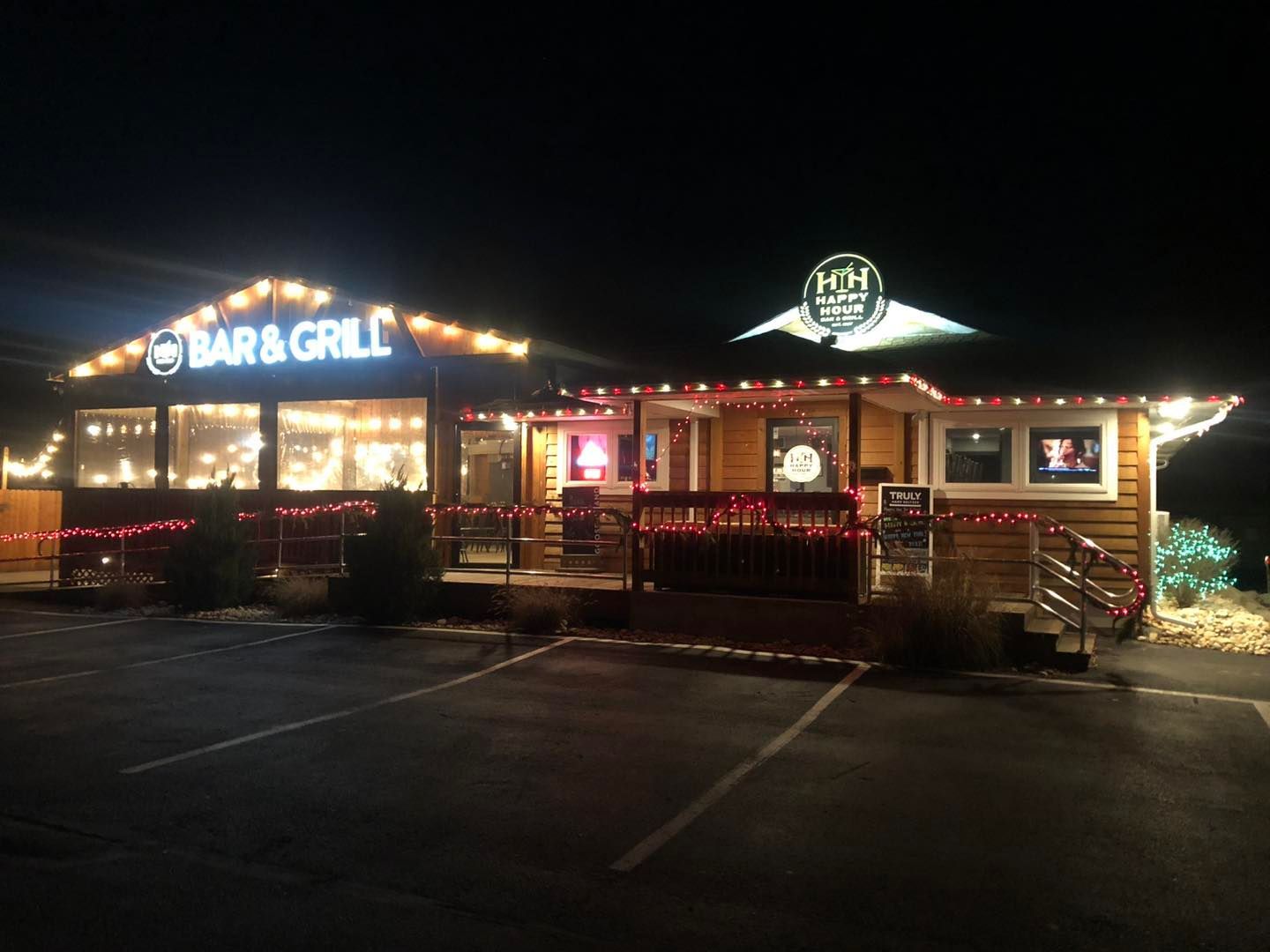 Happy Hour Bar & Grill is lit up at night with christmas lights.
