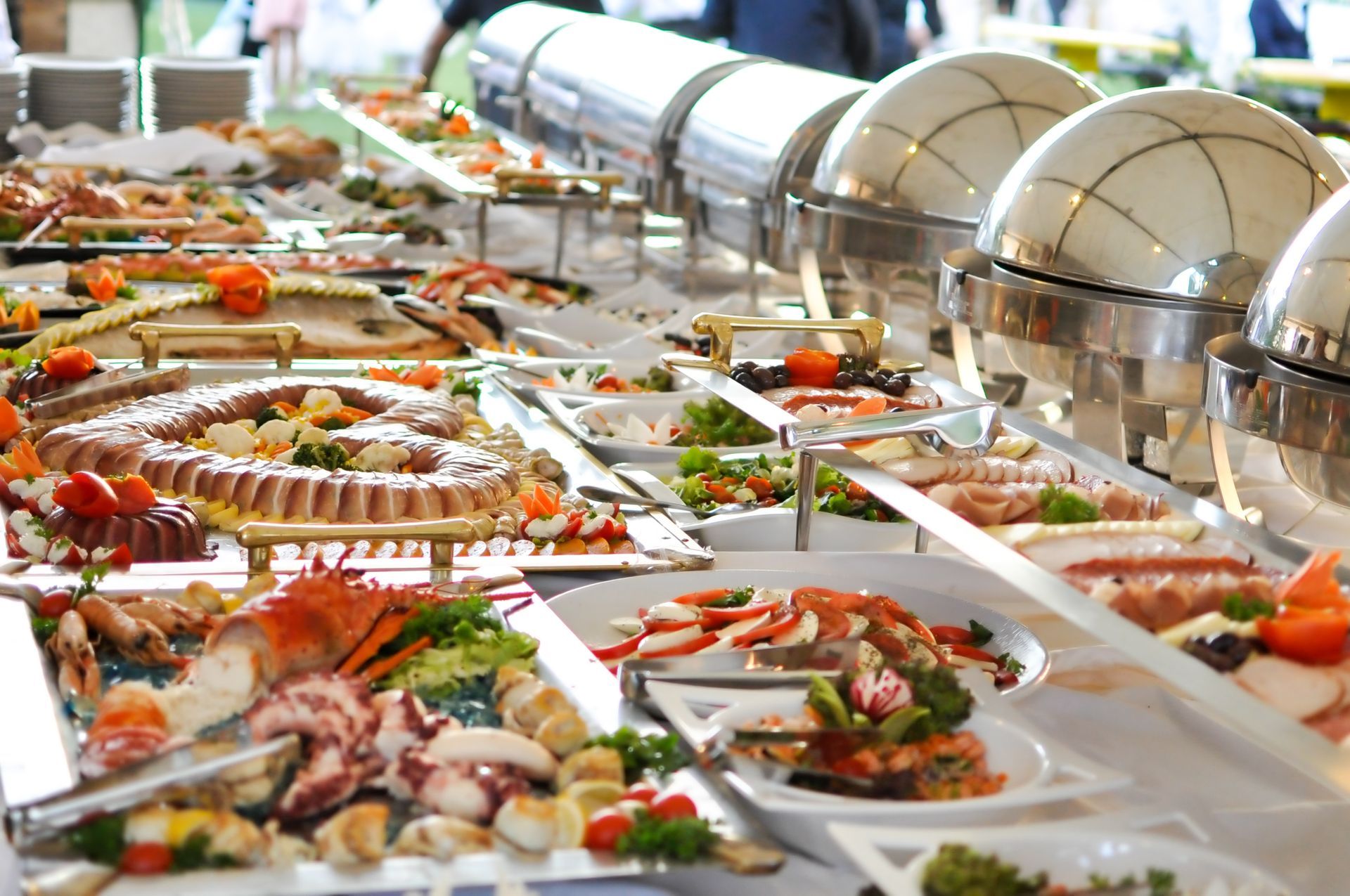 Buffet with various dishes including seafood, salads, and hot entrees in metal chafing dishes.