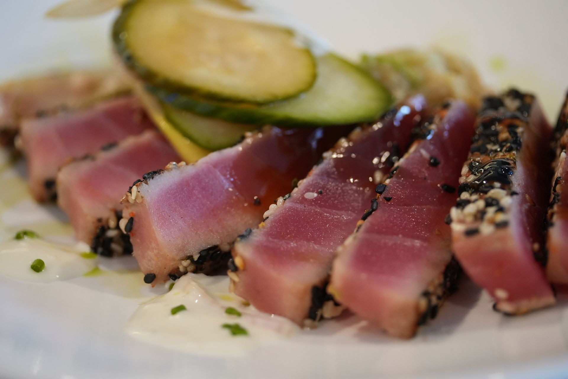 A white plate topped with sliced tuna and vegetables.