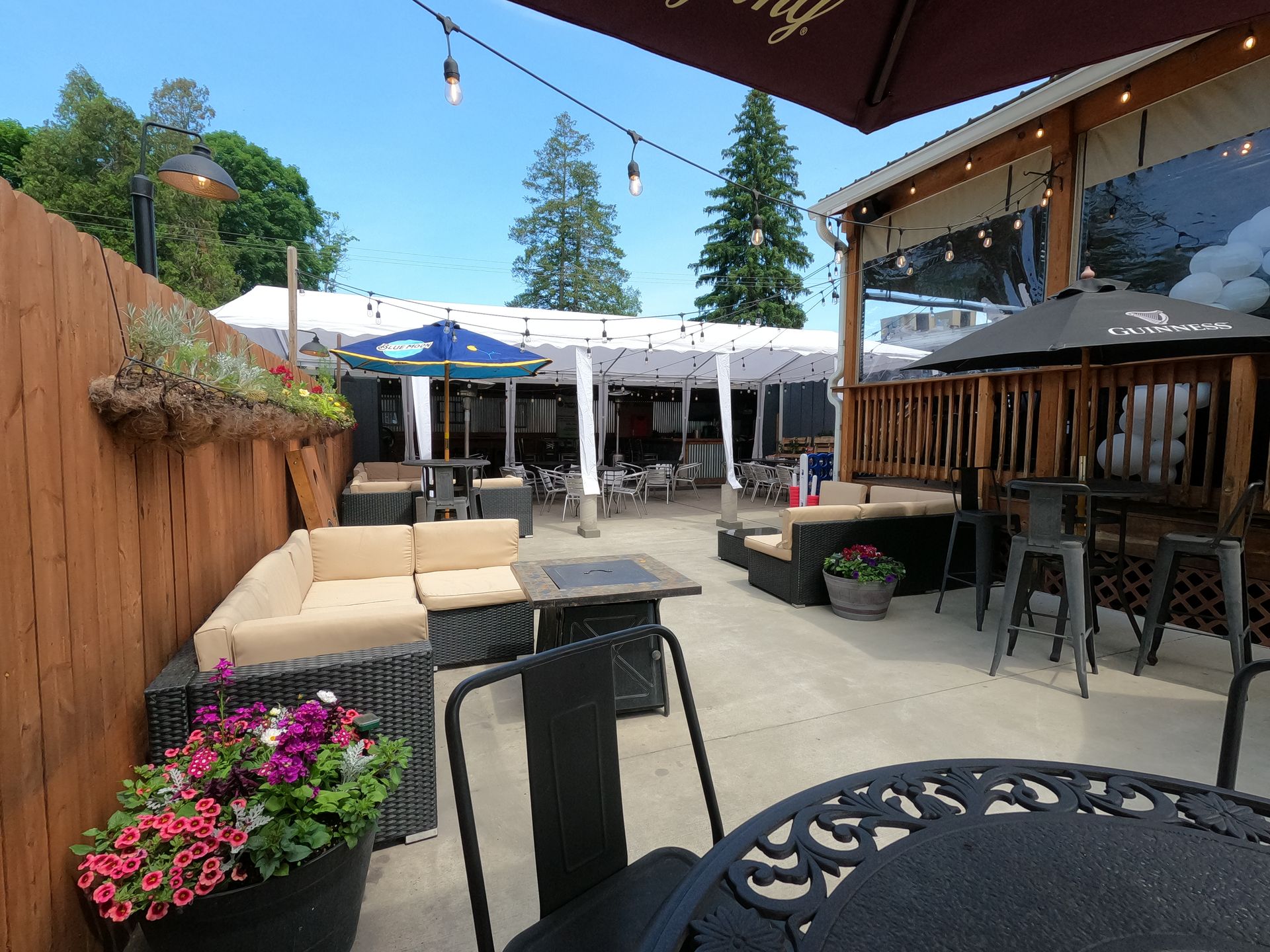 A patio with a table , chairs , umbrellas and a couch.