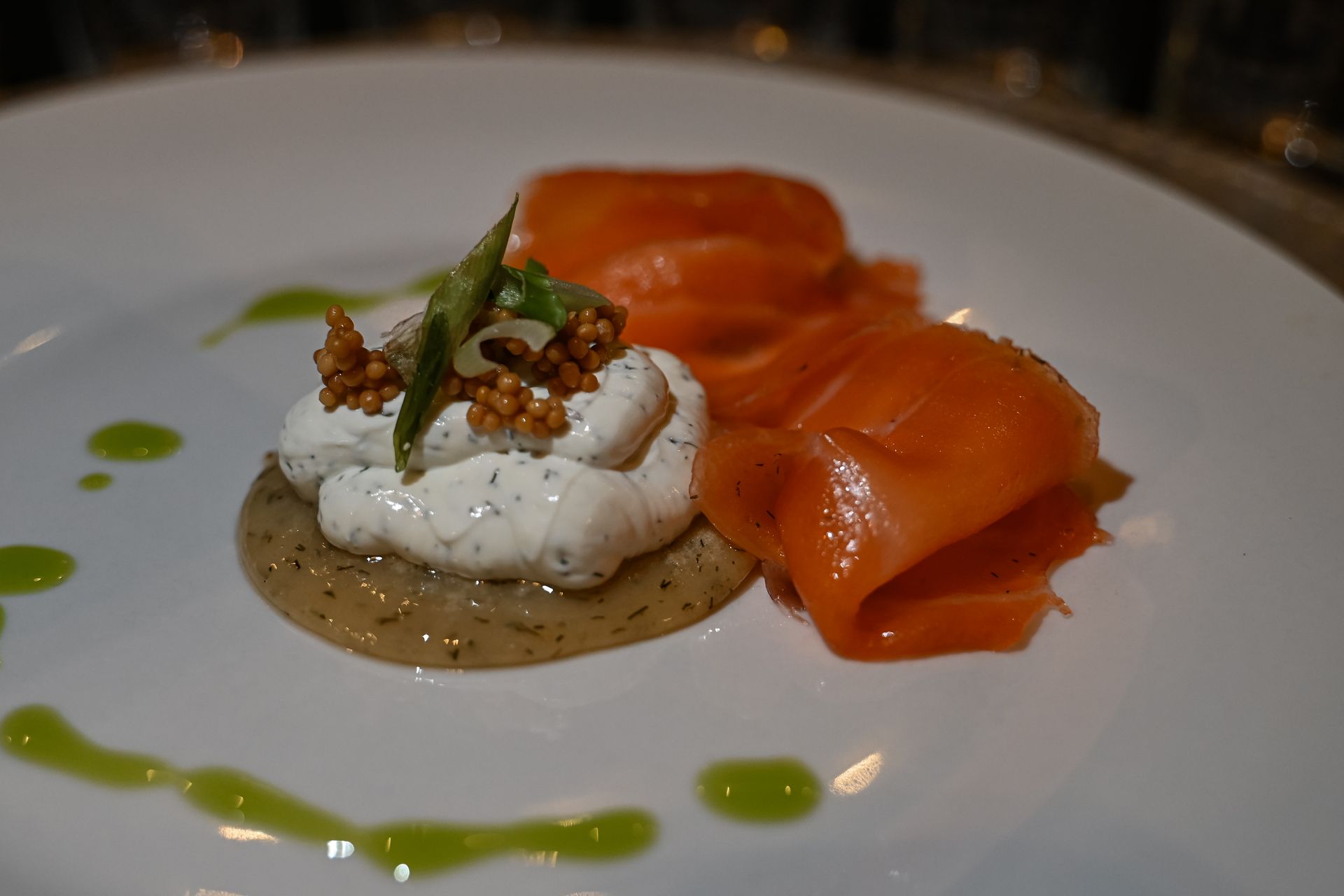 A close up of a plate of food with smoked salmon and whipped cream.