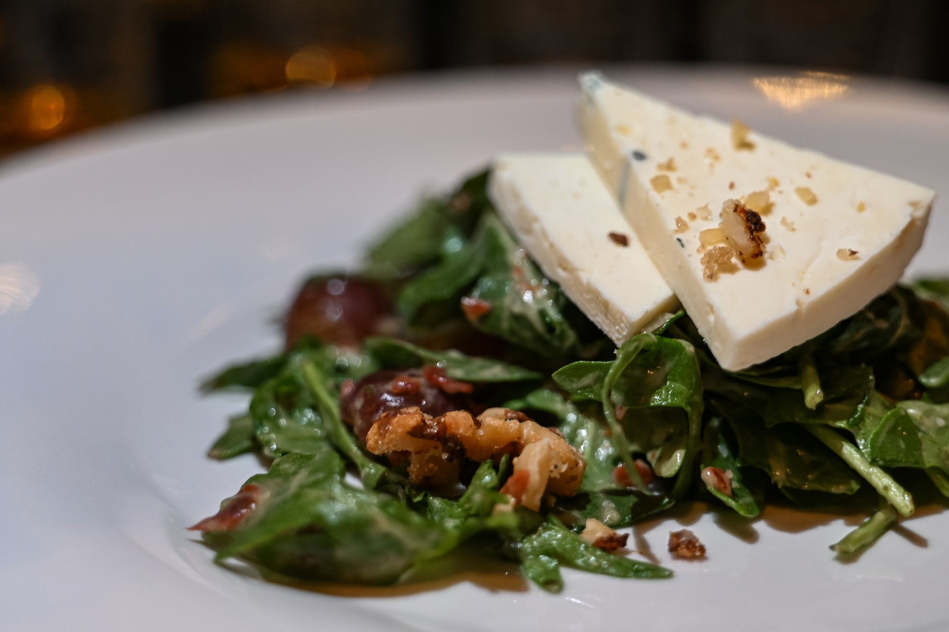 A close up of a salad with cheese and nuts on a plate.