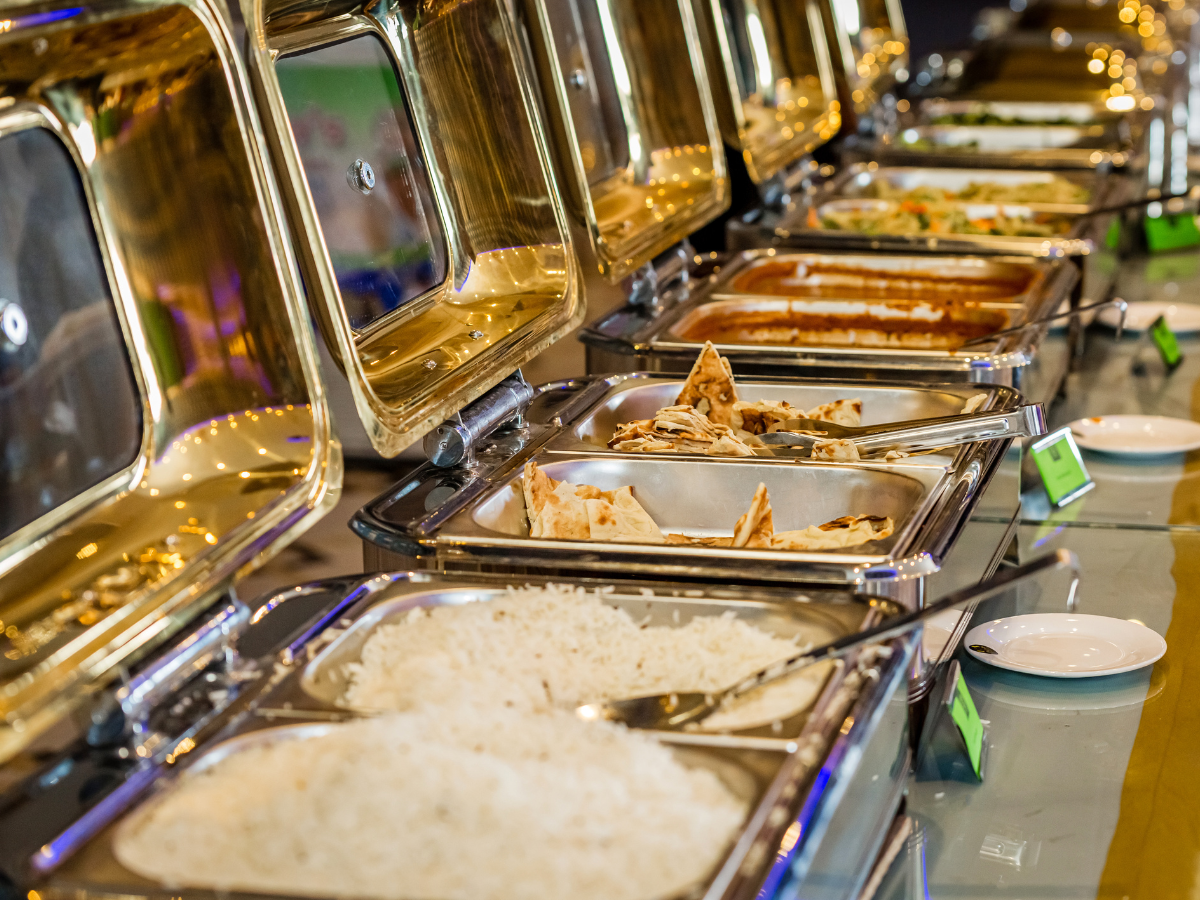 Buffet with various food dishes in stainless steel chafing dishes, at a restaurant.