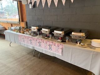 A long table with a white tablecloth and a bunch of food on it at Happy Hour Bar & Grill