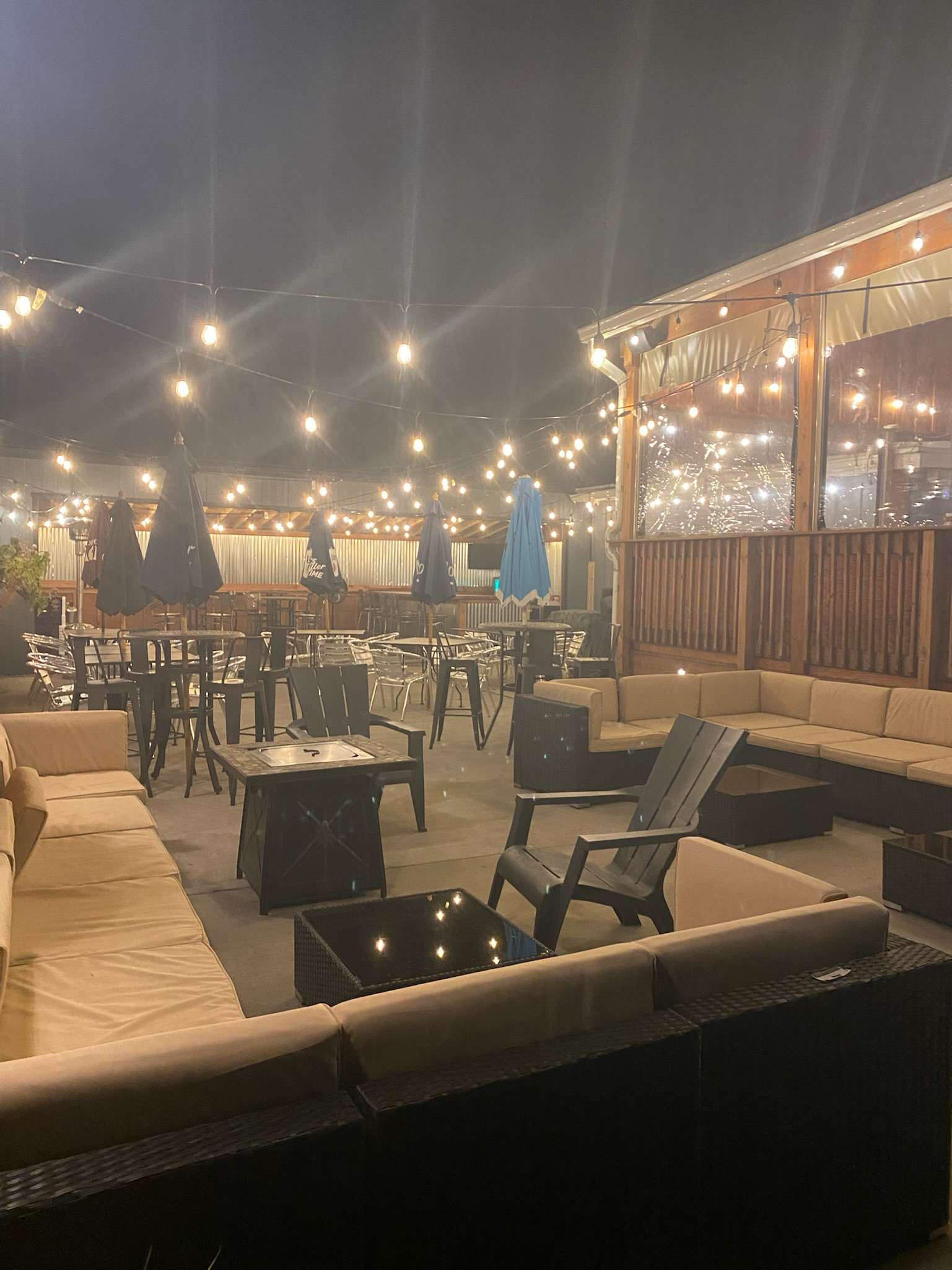 Happy Hour Bar & Grill patio with a lot of furniture and lights at night.