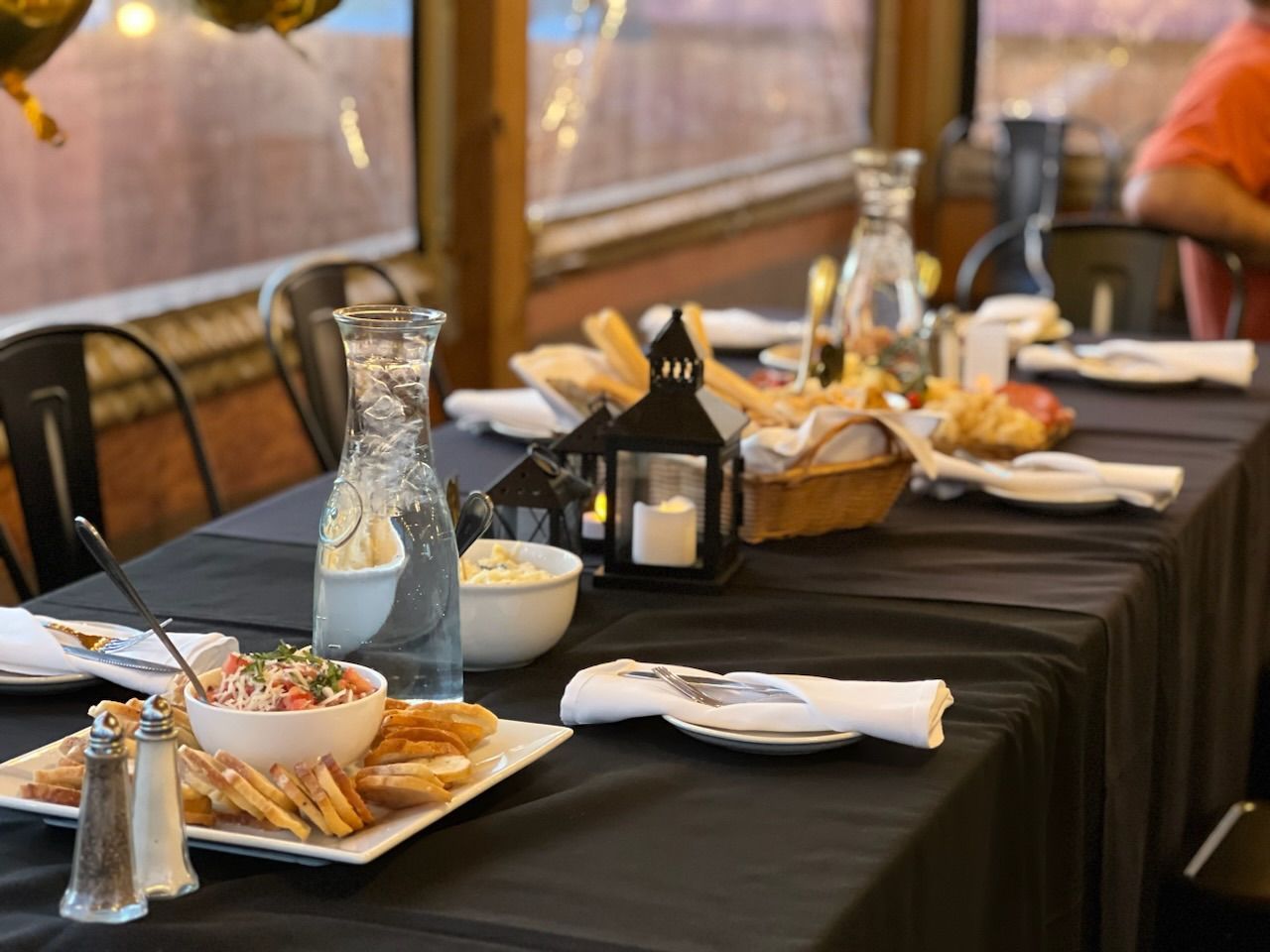 A table with plates of food and candles on it at Happy Hour Bar & Grill