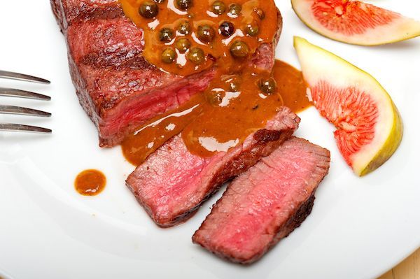A white plate topped with meat and sauce with a fork