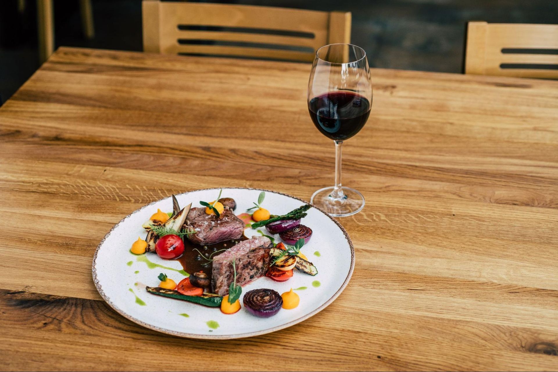 A plate of food and a glass of wine on a wooden table.