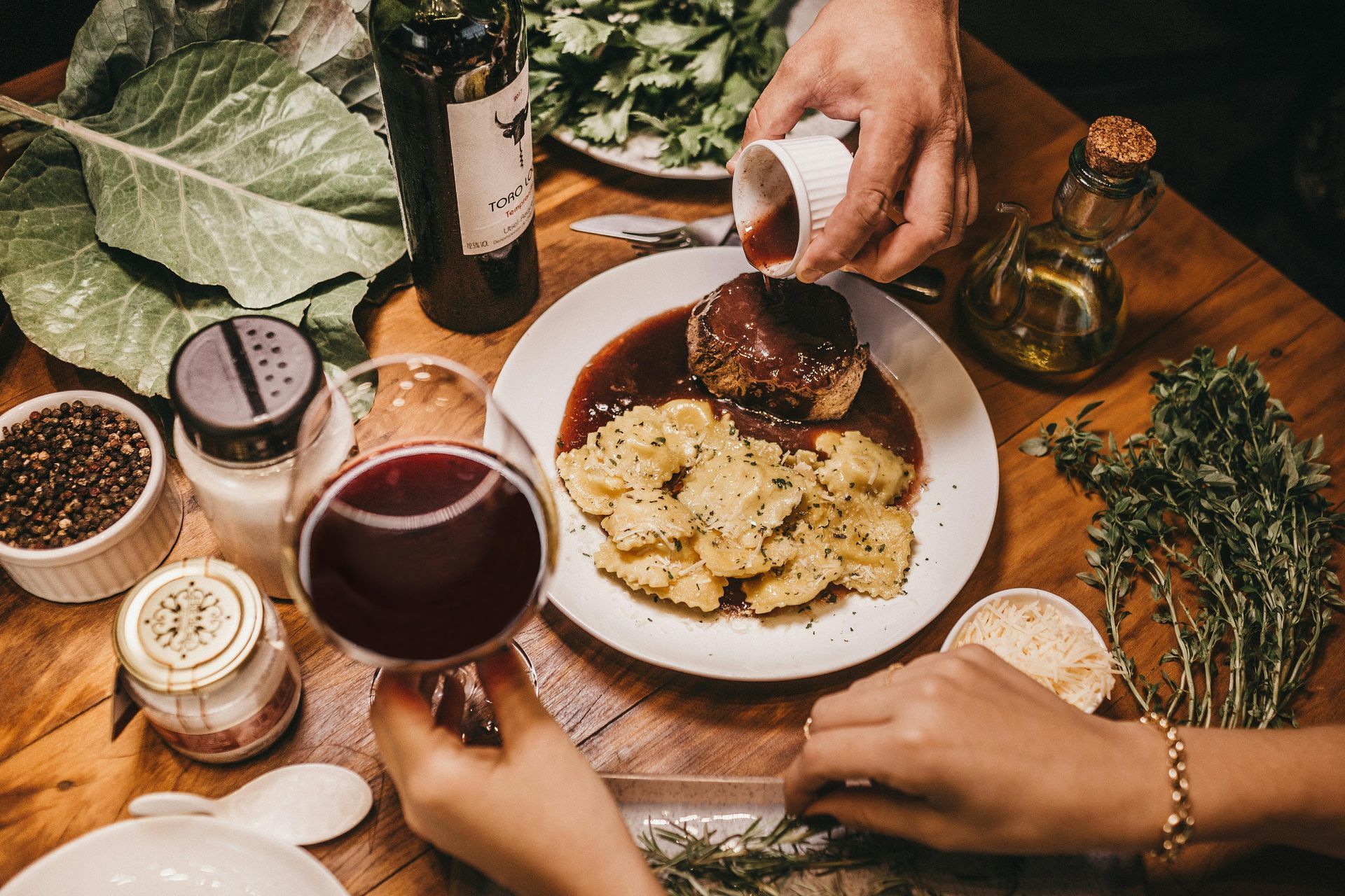 A person is pouring sauce on a plate of food.