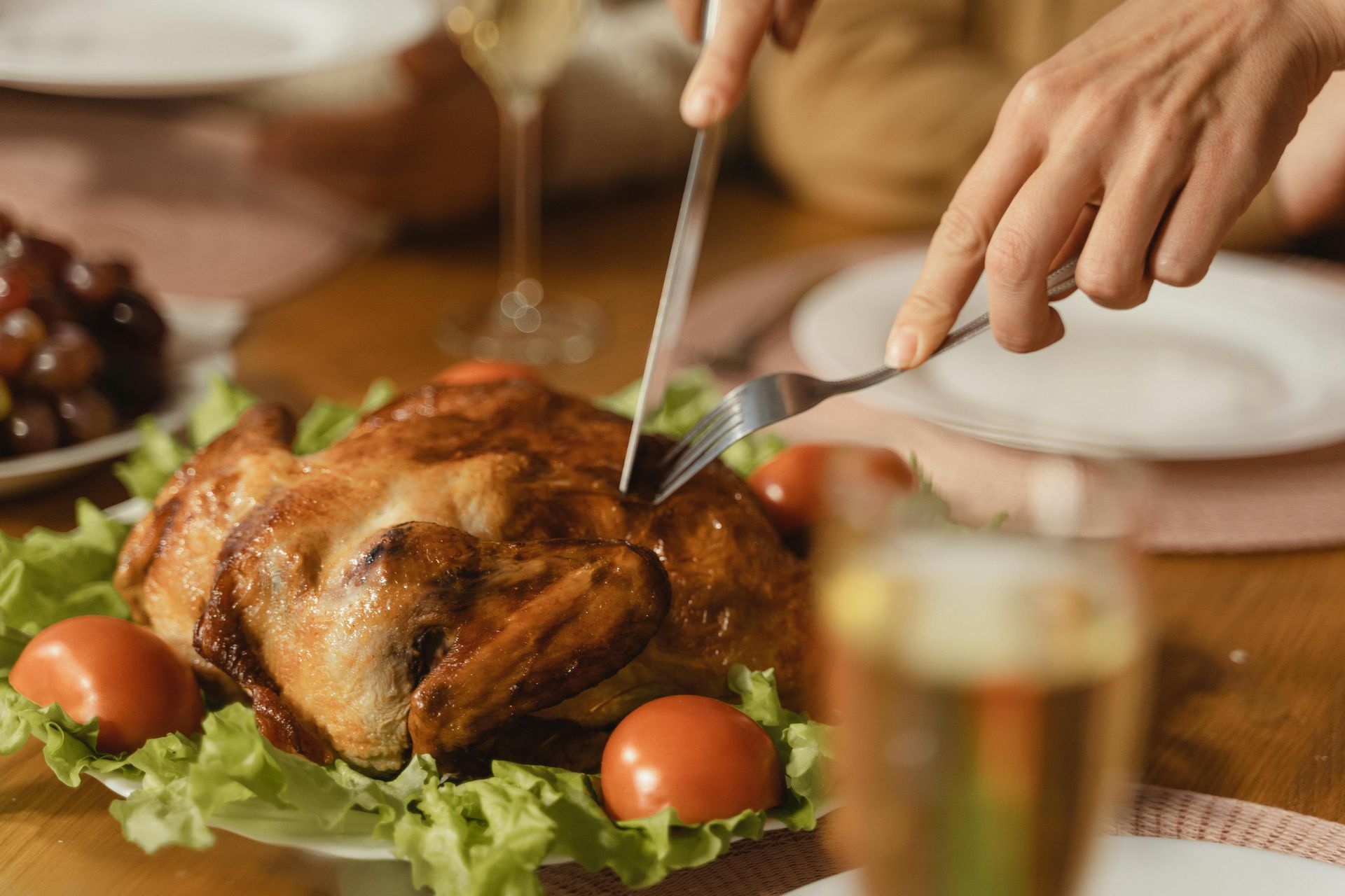 A person is cutting a roasted chicken on a plate.